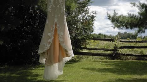 Gorgeous-designer-wedding-dress-blowing-in-the-wind-while-hanging-from-a-tree-on-a-acreage-at-Strathmere-Wedding-and-Event-center-in-Ottawa,-Canada