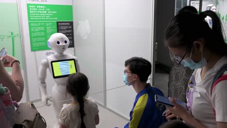Besucher-Interagieren-Mit-Einem-Roboter,-Während-Ein-Junges-Mädchen-Während-Der-„Roboter“-Ausstellung-Im-Hong-Kong-Science-Museum-In-Hongkong-Dessen-Kopf-Berührt