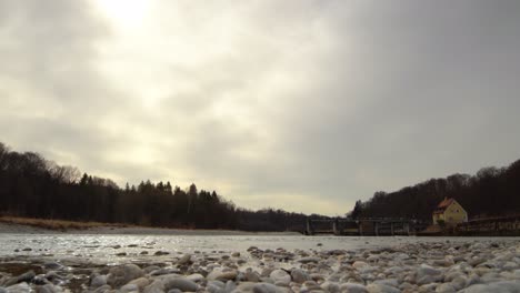 Flowing-Isar-river-at-a-shore-full-of-stones-under-a-cloudy-but-sunny-day