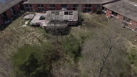 Aerial-Drone-Footage-Dollying-Forward-and-Panning-Down-Towards-an-Abandoned-Hotel-during-Late-Winter