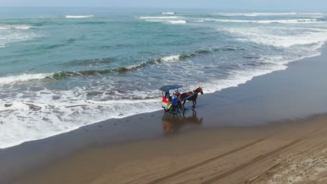 Horse-carriage-riding-on-Parangtritis-beach,-Yogyakarta,-Indonesia,-aerial