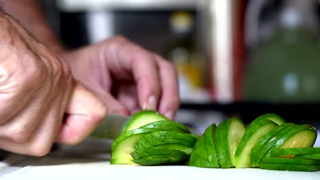 Close-shot-of-a-zucchini-being-chopped-on-a-white-table