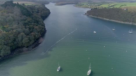 Aerial-view,-tilting-down-over-boats-on-an-estuary-in-Cornwall,-England