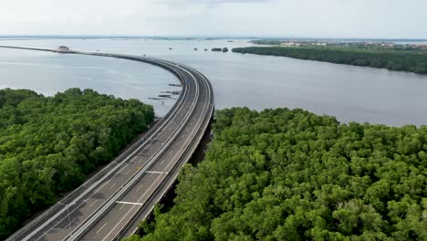 South-of-Mandara-Toll-Road-and-Gerbang-Tol-in-Bali-Indonesia-above-the-Gulf-of-Benoa,-Aerial-dolly-left-shot
