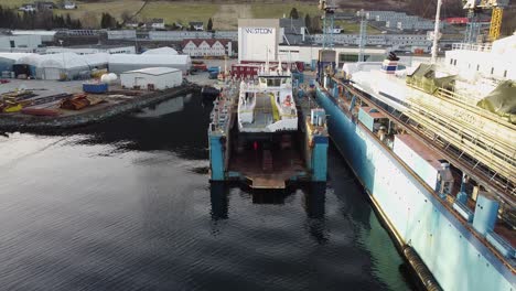 Two-electric-ferries-in-drydock-at-westcon-yards-ølensvåg-norway--Near-to-far-revealing-drilling-rig,-worlds-largest-electric-ferry-Basto-and-hydrogen-ferry-Hydra