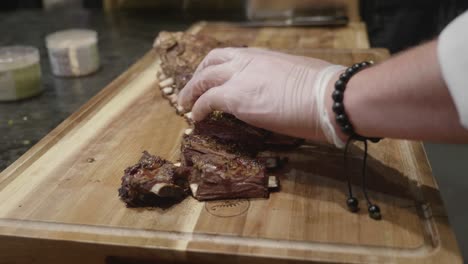 Cutting-beef-ribs-on-wooden-cut-board-at-meat-tasting-event