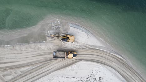 Unique-view-of-a-large-excavator-loading-sand-on-a-dump-truck-for-a-coastal-rejuvenation-city-project
