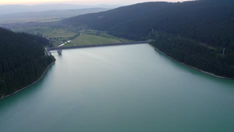 Aerial-View-Of-Frumoasa-Dam-With-Mountain-Views-At-Sunrise-In-Romania