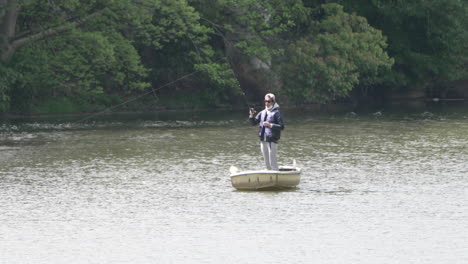 Person-Standing-On-A-Small-Boat-At-Peaceful-River-With-A-Fishing-Rod-In-Tokyo,-Japan