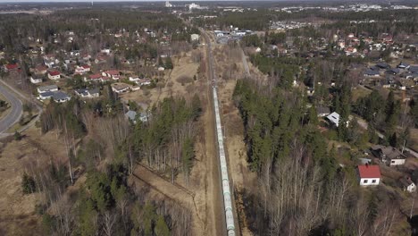 Aerial-view-of-a-long-freight-train-travelling-through-residential-areas