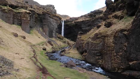 Island-Wasserfall-In-Der-Schlucht-Mit-Wanderweg-Und-Fluss-Kvernufoss