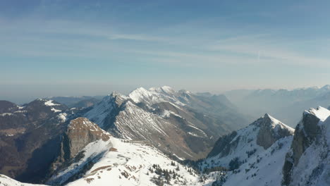 Aerial-of-beautiful-valley-surrounded-by-mountain-summits-and-covered-in-snow