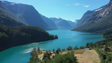 Lovatnet-lake---The-famous-turquoise-colored-glacier-lake-hidden-in-the-Norwegian-valley-Lodalen---Aerial-from-shoreline-showing-panoramic-view-of-lake-and-stunning-mountain-surroundings
