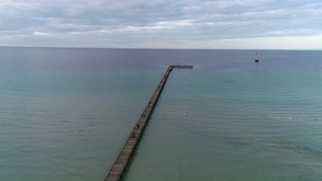 Drone-Overlooking-long-pier-and-blue-ocean-with-old-sailing-ship-Rye