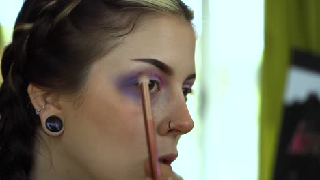 Applying-purple-eye-shadow-in-front-of-pallet-mirror