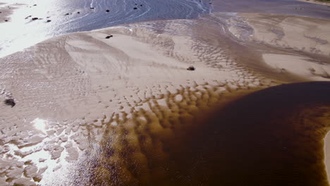 Aerial---Unique-sand-patterns-at-Bot-River-mouth,-brown-tannin-rich-waters-of-lagoon