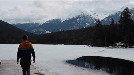 Man-walking-out-toward-frozen-lake-in-British-Columbia,-Canada