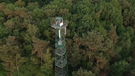 Flying-towards-forest-watchtower-near-dirt-road,-aerial-view