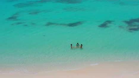 Overhead-view-of-three-women-tourists-enjoying-turquoise-ocean-of-Pedernales