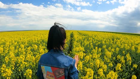 Back-View-Of-A-Girl-Walking-On-The-Rapeseed-Farm-In-The-Countryside---slow-motion