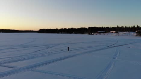 Tourist-Stands-At-The-Frozen-River-In-Rovaniemi-City-During-Golden-Hour