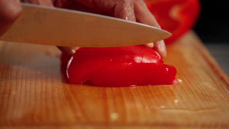 Red-Bell-Pepper-being-sliced-in-slow-motion-on-a-wooden-cutting-board