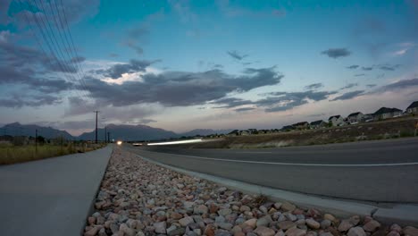 Traffic-speeds-along-the-highway-as-an-evening-cloudscape-passes-over-the-mountains---static-time-lapse