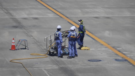 Ground-Crews-In-Uniforms-And-Safety-Hard-Hats-Talking-At-The-Tarmac-Of-Haneda-Airport-In-Tokyo,-Japan