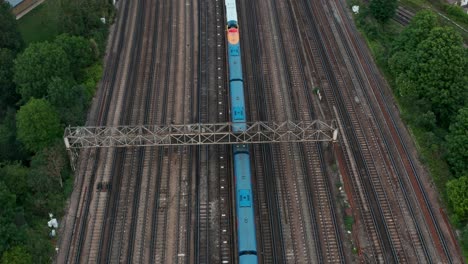 Pan-up-drone-shot-from-expansive-railway-train-tracks-to-London-Skyline
