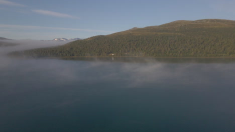 Lago-Sjodalsvatnet-En-Una-Mañana-Brumosa-Con-Montañas-Forestales-En-El-Parque-Nacional-De-Jotunheimen,-Vaga,-Noruega