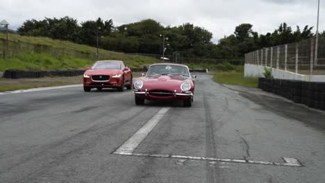 vintage-red-car-on-road-jaguar-i-pace-together-with-new-jaguar-i-pace-electric