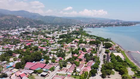 Aerial-drone-of-capital-city-Dili-in-Timor-Leste,-South-East-Asia,-high-up-and-lowering-towards-buildings,-traffic-and-ocean