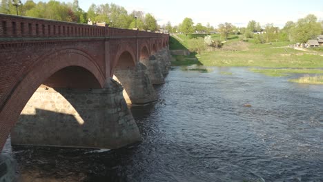 Largo-Puente-De-Ladrillo-Antiguo,-Kuldiga,-Letonia-A-Través-Del-Río-Venta