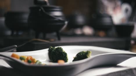 slow-motion-empty-plate-of-vegetables-with-a-few-pots-on-a-table-busy-cooking