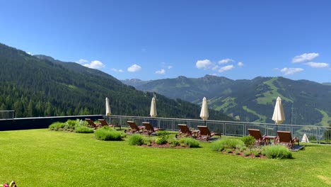 Pan-shot-of-luxury-garden-with-tutored-lawn-in-front-of-gigantic-mountain-landscape-during-summer-day-in-Austria