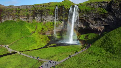 Mächtiger-Wasserfall-Seljalandsfoss,-Der-An-Einem-Sonnigen-Tag-In-Island-Plätschert-Und-Einen-Regenbogen-Erzeugt---Luftaufnahme