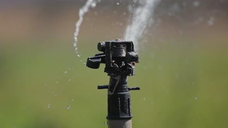 Nahaufnahme-Des-Kopfes-Einer-Sprinkleranlage,-Der-Wasser-Zur-Bewässerung-Von-Ackerland-Versprüht,-Scharfer-Fokus-4k
