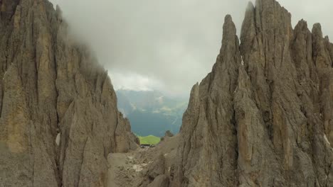 Fly-between-mountain-tops-covered-with-rainy-clouds,-Dolomites-Italy