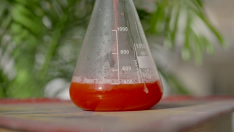 Slow-motion-colourful-measure-of-red-liquid-pouring-into-glass-medical-flask-close-up