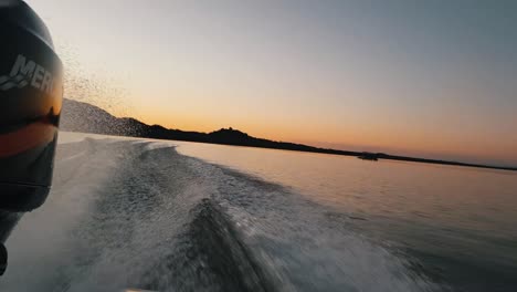 Blick-Von-Hinten-Auf-Ein-Bassboot,-Das-Schneller-Fährt,-Mit-Einem-Atemberaubenden-Sonnenuntergang-In-Der-Ferne
