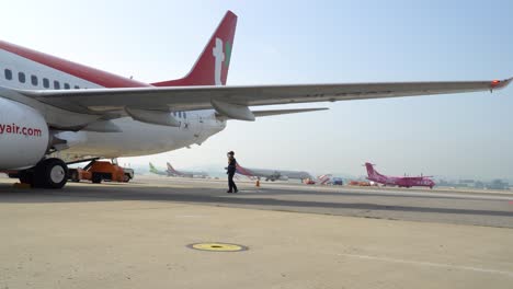 Flughafenarbeiter-In-Uniform,-Der-Unter-Der-Tragfläche-Einer-T&#39;Way-Air-Boeing-Läuft,-Die-An-Der-Rampe-Des-Inlandsflughafens-Gimpo-In-Seoul,-Südkorea,-Geparkt-Ist