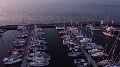 Barcos-De-Vela,-Vista-Superior-En-El-Puerto-Deportivo,-Atracados-En-El-Muelle-Durante-La-Puesta-De-Sol-03