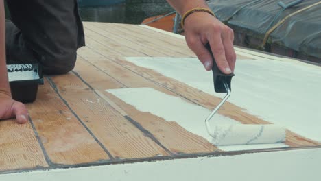 Applying-thinned-coat-white-primer-on-wooden-boat-roof-with-roller