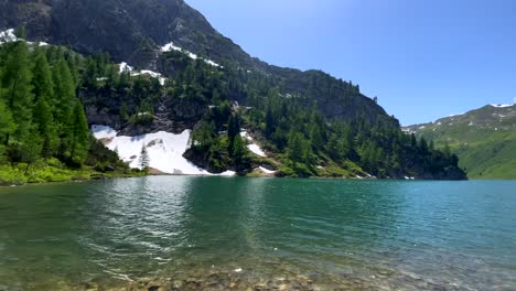 Panorama-shot-of-nature-Lake-between-Austrian-mountains-covered-with-snow-in-summer