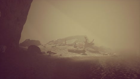 Felsklippe-Mit-Sandstrand-Im-Tiefen-Nebel