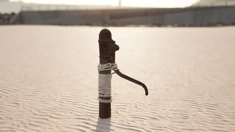 Rusty-old-metal-water-pump-on-sand-beach