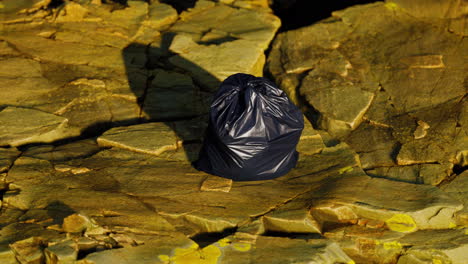 black-trash-bag-lay-on-a-rocky-beach