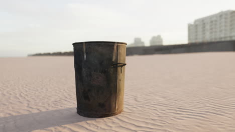 Gray-metal-garbage-bin-or-trash-can-on-the-beach