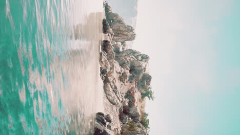 vertical-video-of-large-rock-island-in-the-middle-of-the-sea-water