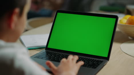 Unknown-boy-using-mockup-computer-home.-Schoolboy-looking-laptop-green-screen